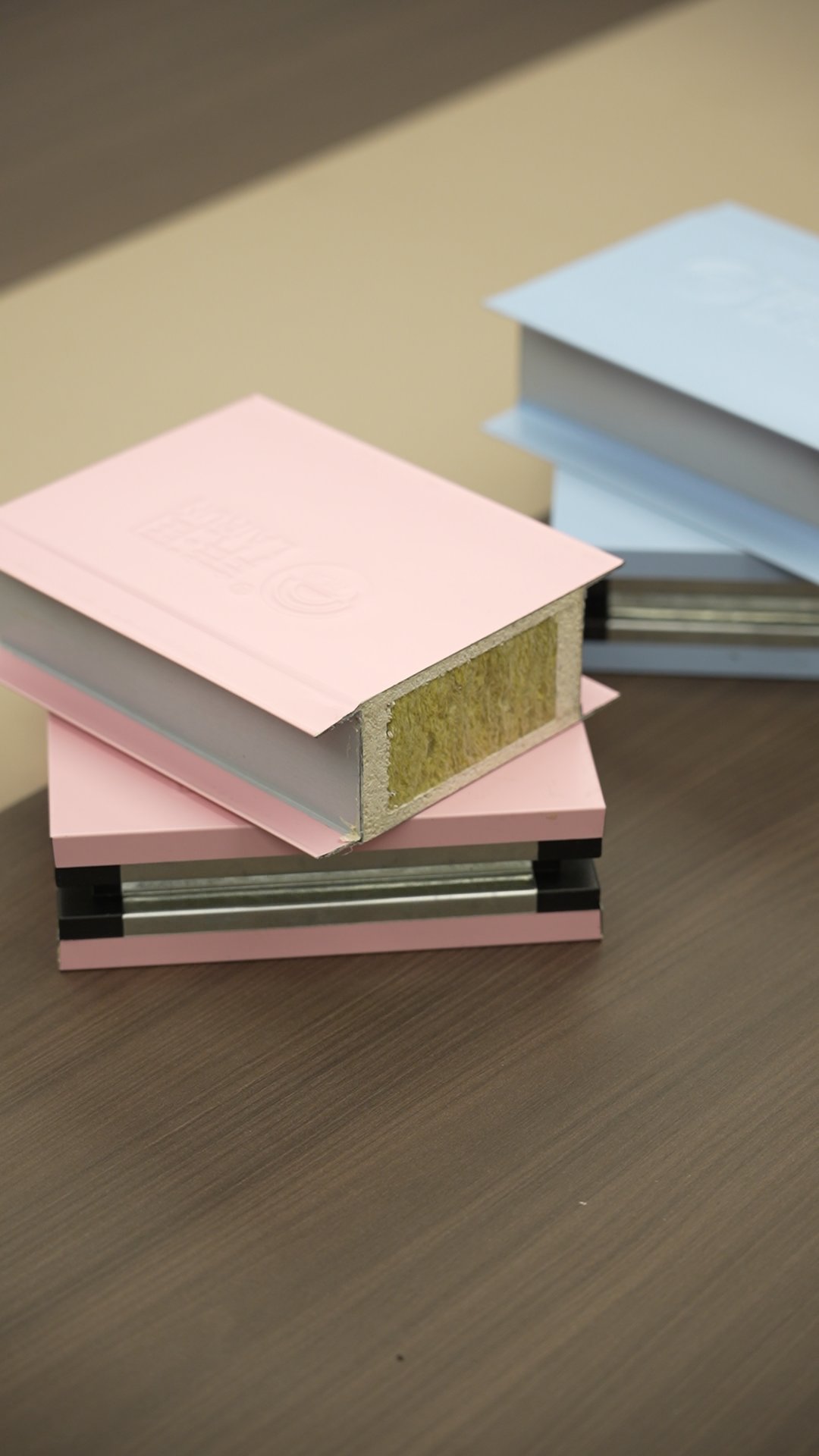 Pink-faced rockwool core sample: two sample pieces with a yellow fibrous rockwool core visible at the edge; a sample picture, not a specific panel model.